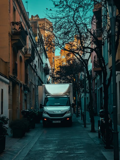 Image showing a team of movers from officeremovals.org.uk loading a variety of packing materials into a white cargo van parked on a city street in front of an ornate stone building with barred windows